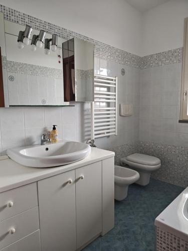 a white bathroom with a sink and a toilet at Sunset Penthouse in Gessate