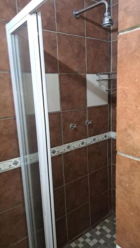 una ducha con puerta de cristal en un baño en At Home Guest House, en Postmasburg