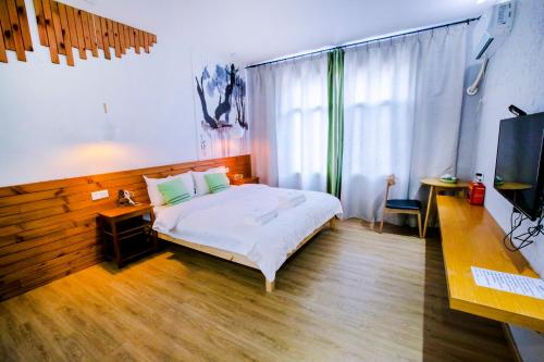 a bedroom with a bed and a desk and a television at Zhangjiajie Forest Park Youth Hostel in Zhangjiajie