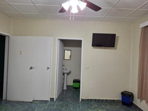 a room with a toilet and a tv on the wall at Hostal primaveras nest centro santa ana in Santa Ana