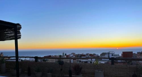 a view of the sunset from a balcony with plants at Monza Surf House in Tamraght Ouzdar