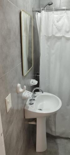 Un baño con un lavabo blanco y un espejo. en Laguna Azul, en Río Gallegos