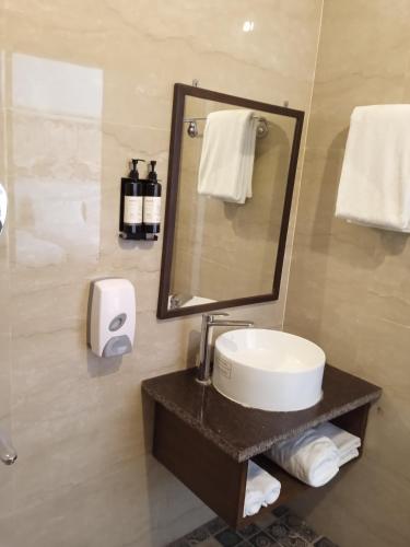a bathroom with a sink and a mirror and towels at Navut Homestay - Serenity Among Coffee Plantations in Virajpet