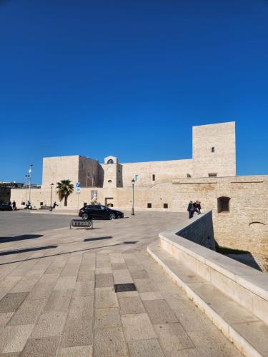 a large brick building with a car parked in a parking lot at Rossè B&B Holiday House in Trani