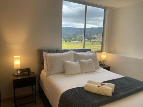 a bedroom with a bed with a large window at Apartamento en Paipa frente al lago in Paipa