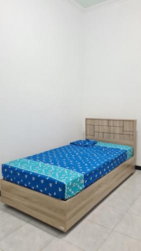 a bed with blue sheets and a wooden frame at Rumah Sri Pasti in Jrebeng-wetan