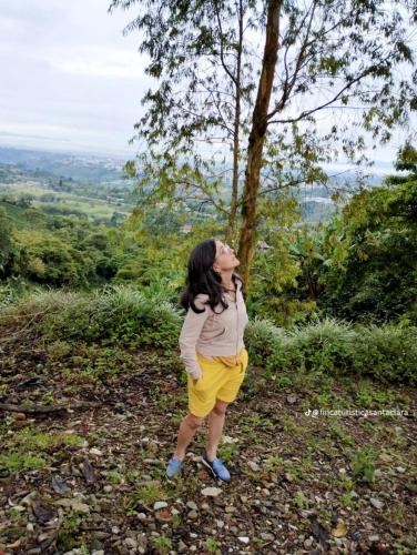 a woman standing on a hill looking up at a tree at Finca Hotel Santa Clara in Calarcá