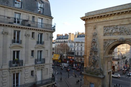 a building with an arch in the middle of a city at Hôtel Allety in Paris