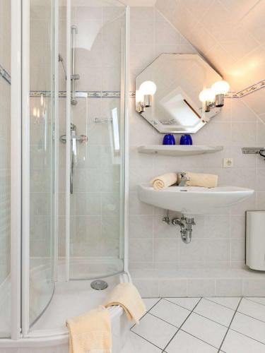 a white bathroom with a shower and a sink at Haus Seeflieger in Westerland