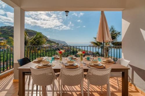 a dining room table with chairs and a view of the ocean at Melro's Place by Stay Madeira in Ponta do Sol