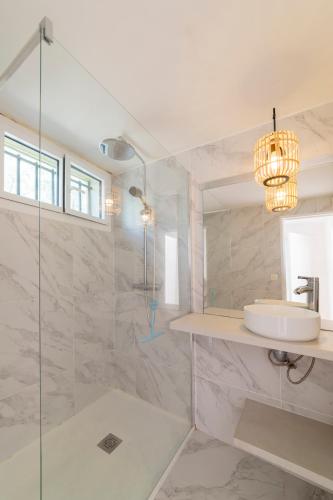 une salle de bain blanche avec un lavabo et une douche dans l'établissement VILLA BORD DE MER 6 COUCHAGES AVEC JARDIN ET GARAGE, à La Grande Motte