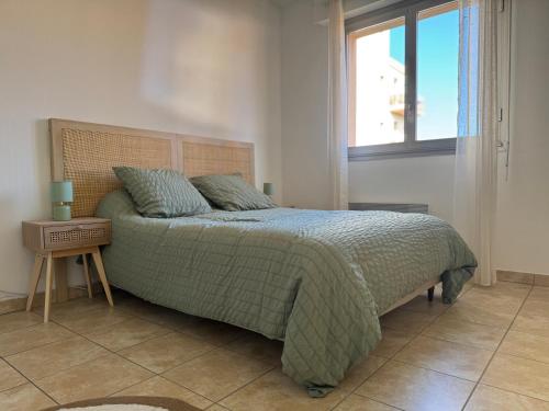 - une chambre avec un lit doté d'une couette verte et d'une fenêtre dans l'établissement Le botaniste, à Perpignan