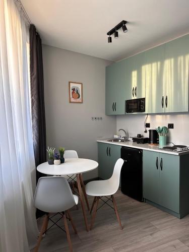 a kitchen with green cabinets and a white table and chairs at Maximus apartments in Mestia in Mestia