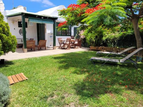 a yard with a table and chairs and a tree at VV Sweet Flamboyan Playaflor 1 "by henrypole home" in Maspalomas