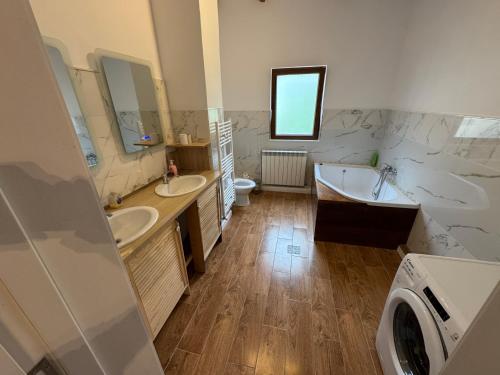 Un baño con dos lavabos, una bañera y un inodoro. en Casa Olivia, en Buşteni
