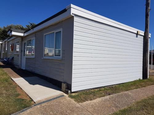 a black and white building next to a sidewalk at 112 Sandown Holiday Park, Wifi, sleeps 4 in Sandown