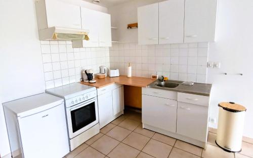 une petite cuisine avec des armoires blanches et un évier dans l'établissement Grand T2, RDC avec jardin, à Trets