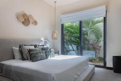 a bedroom with a white bed and a large window at Increíble Villa 2 piscinas 4hab hasta 14 personas in Tulum