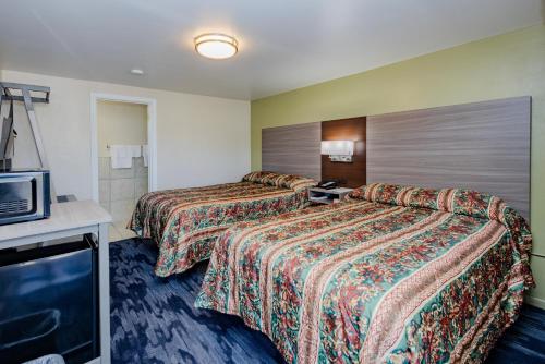a hotel room with two beds and a flat screen tv at Budget Inn Columbus in Lockbourne