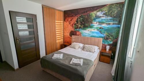 a bedroom with a painting of a river at Hotel MAGNAT in Głogów Małopolski