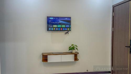 a flat screen tv on a wall with a potted plant at La Vita Hotel in Ấp Bàu Bàng