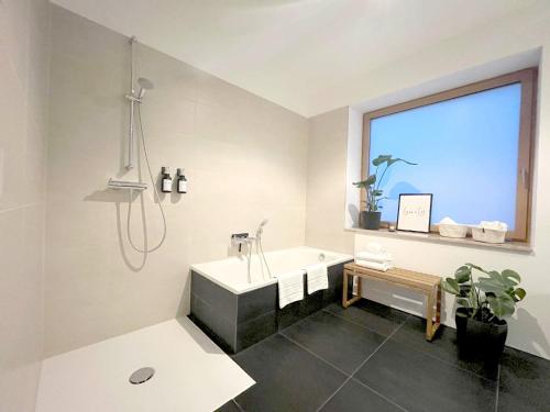 a bathroom with a tub and a sink and a window at Blueberry Living - Wohlfühl-Apartment Starnberger See, Design, Sport & Natur in Tutzing