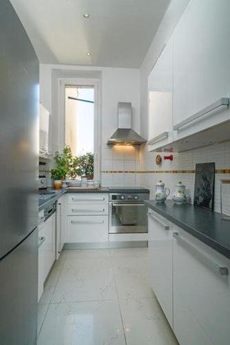 une grande cuisine avec des armoires blanches et une fenêtre dans l'établissement Good sleeping, à Cannes