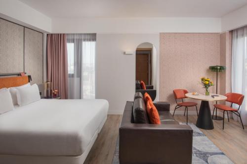 a hotel room with a bed and a couch and a table at NH Catania Centro in Catania