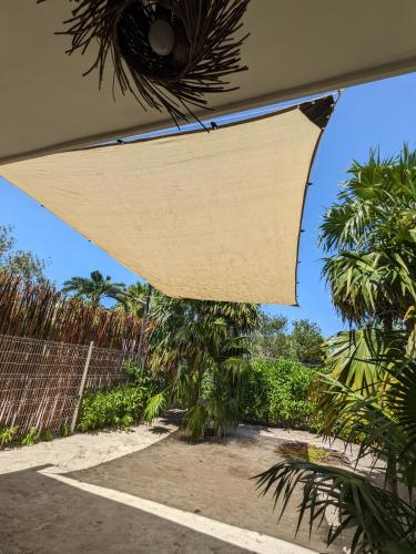 awning over a patio with palm trees and a fence at Casa Foto Estudios in El Cuyo