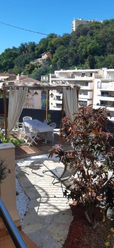 une terrasse avec une table, un arbre et des bâtiments dans l'établissement Chambre d'hôtes, à Menton