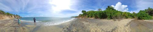 a person standing on a sandy beach near the ocean at Rooster Run Camping is a - rooftop & elevated camping experience! Incredible views of The Rain Forrest and Culebra across the Atlantic Ocean - Tents, towels, comfortable Air Beds, Warm Shower-Central Location- 5 beaches -25 min walk & Ferry is 20 min in Vieques