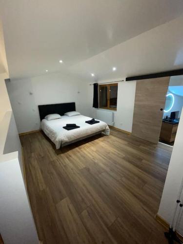 Un dormitorio con una cama y suelo de madera. en Maison du Tripot, en Ligny-en-Barrois
