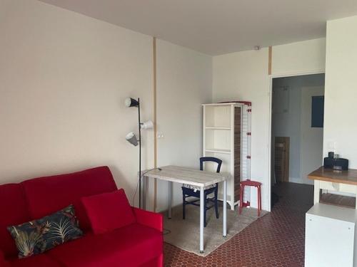 ein Wohnzimmer mit einem roten Sofa und einem Tisch in der Unterkunft Un Cottage à la Mer in Le Pouliguen