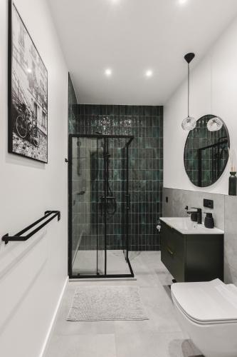 a bathroom with a shower and a toilet and a sink at Dzirnavu Apartment in Riga