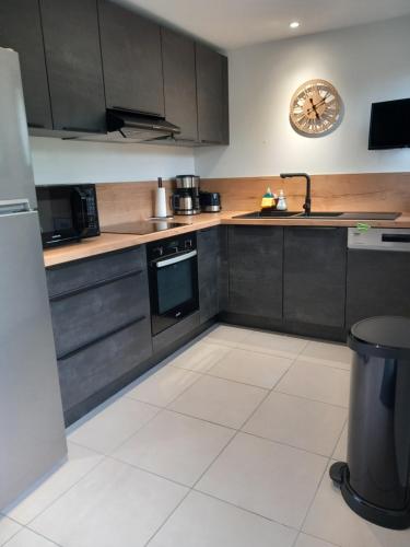 a kitchen with black cabinets and a clock on the wall at Bella Loire in Le Monteil