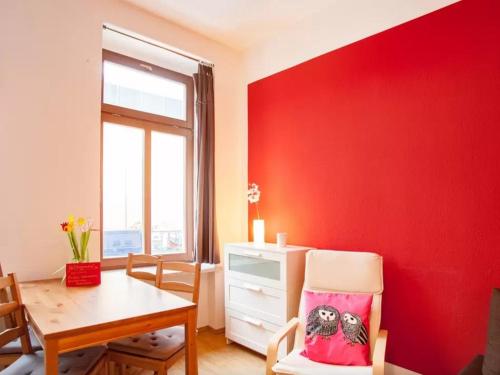 a dining room with a red wall and a table at Im Herzen - Zentral in Leipzig in Leipzig
