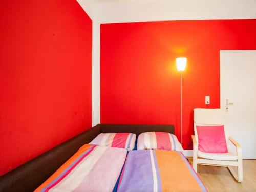 a bedroom with red walls and a bed and a chair at Im Herzen - Zentral in Leipzig in Leipzig