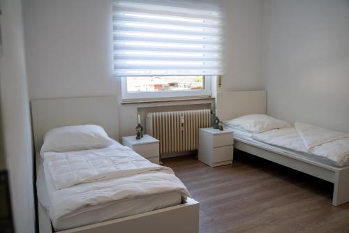 two beds in a small room with a window at FeWo 10P Küche TV WF in Salzbergen