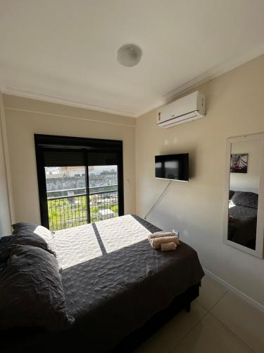 a bedroom with a large bed and a window at Hostel APÊ DO CRIS in Florianópolis