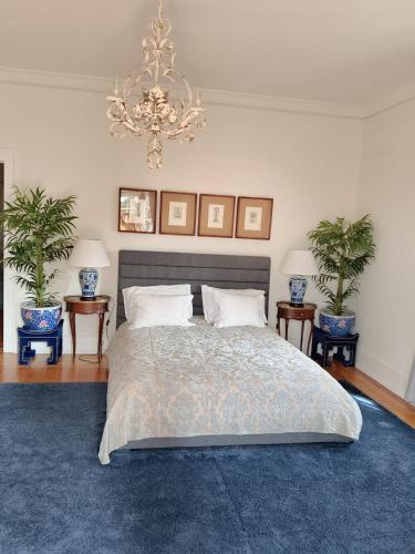 a bedroom with a bed with a chandelier and two plants at Villa Casa do Cruzeiro in Estoril