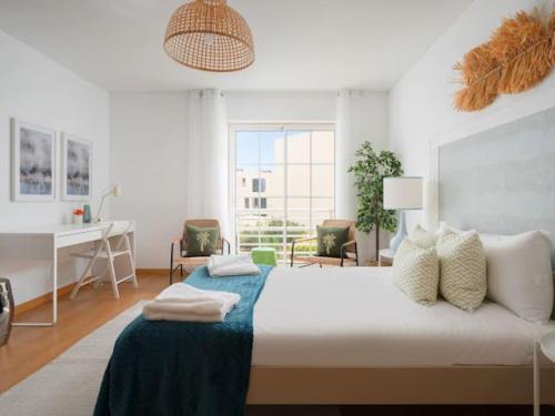 a white bedroom with a large bed and a desk at Sweet Summer Apartment - Cabanas in Cabanas de Tavira