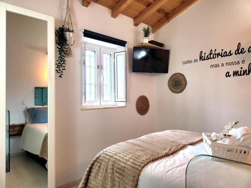 a bedroom with a bed and a television on the wall at Casinha da Esquina in Amieira