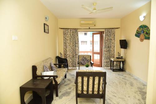 ein Wohnzimmer mit einem Sofa, Stühlen und einem Fenster in der Unterkunft Coconut Grove Holiday Apartment in Varca