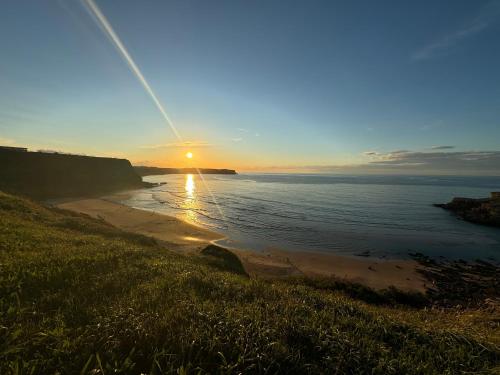 a sunset on a beach with the sun setting at Apartamentos Olga Cantabria 2 in Polanco