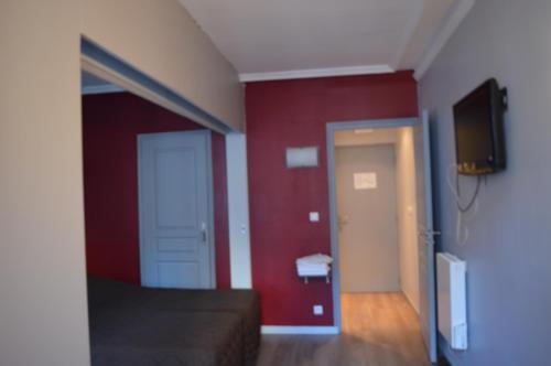 - une chambre dotée d'un mur rouge et d'une porte avec une télévision dans l'établissement Hôtel Allety, à Paris