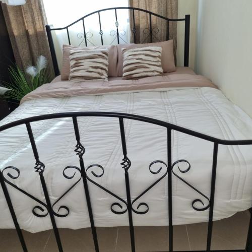 a black metal bed with white sheets and pillows at Escape to comfort properties in Abu Dhabi