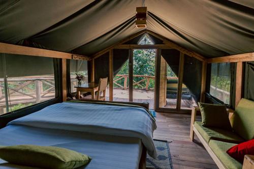 a bedroom in a tent with a bed and a couch at Ruhondo Island Retreat in Ruhondo