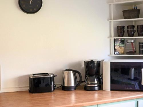 a counter with two coffee makers and a clock on a wall at Welcoming cottage near the sea-By Traum in Mellbystrand