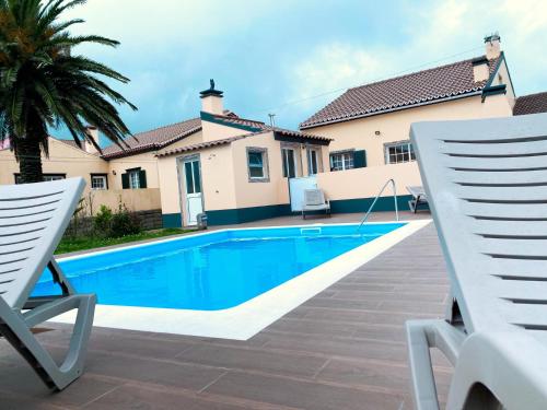 a villa with a swimming pool and two chairs at Sea House in Povoação