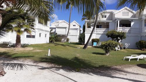 a white house with palm trees in front of it at Dolce Vita Anse Margot in Marigot